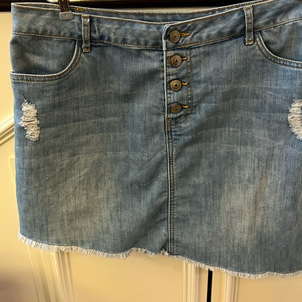 Blue denim jeans skirt with front buttons and asymmetrical hem.